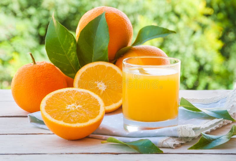 Frutti delle arance e del succo d'arancia fresco con le foglie all'aperto fotografia stock Frutti delle arance e del succo d'arancia fresco con le foglie all'aperto fotografia stock