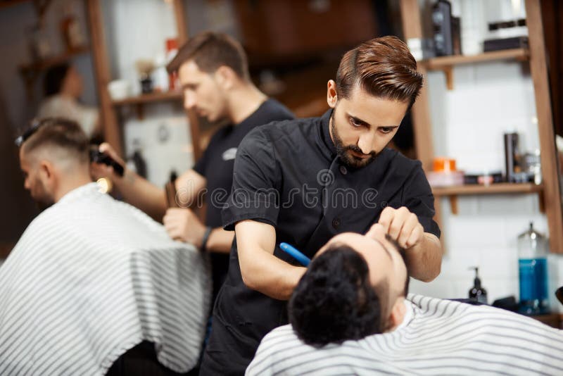 Fryzjer w czarnym tnącym chlebie dla brunet mężczyzna zdjęcia stock Fryzjer w czarnym tnącym chlebie dla brunet mężczyzna zdjęcia stock