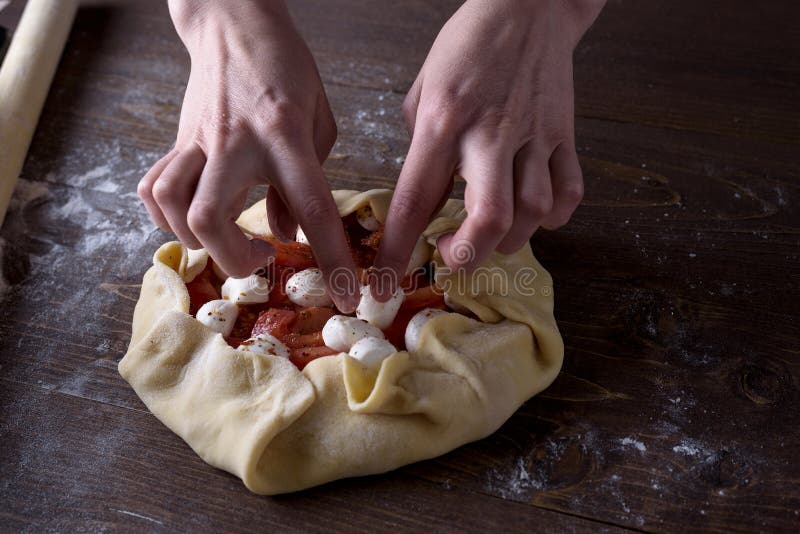 Främre sikt av processen av matlagninggrönsakkex, pizza händer för kvinna` s lägger ut mozzarellaost på tomater och zucchinin royaltyfri bild Främre sikt av processen av matlagninggrönsakkex, pizza händer för kvinna` s lägger ut mozzarellaost på tomater och zucchinin royaltyfri bild