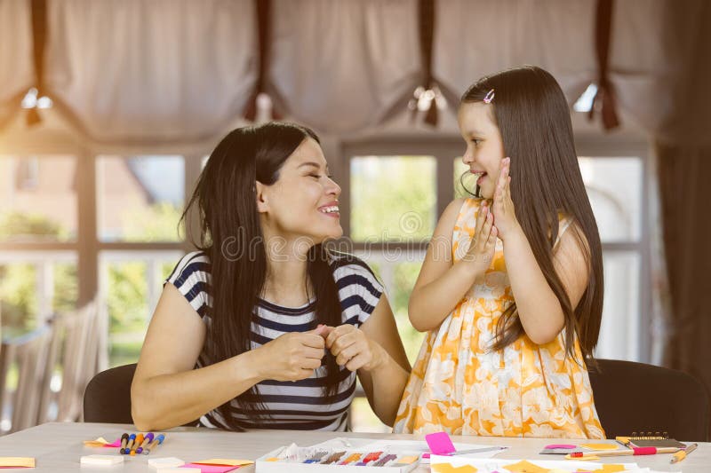 Fröhliche Brunette asiatische Lehrerin und ihr kleines Mädchen. lizenzfreies stockfoto