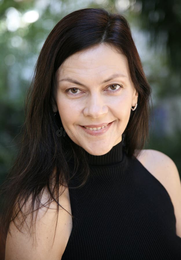 Fröhliche Brunette Frau 51 Jahre alt mit langen Haaren und Make-up in einem schwarz modischen Rollkragen lizenzfreies stockfoto
