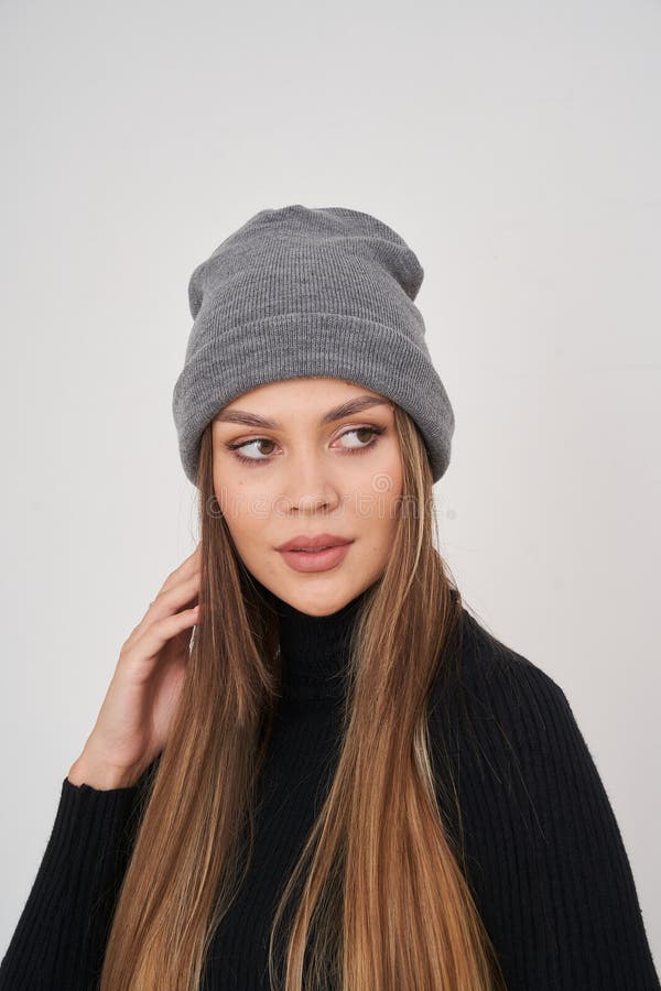 Fröhliche Brunette-Frau in stilvollen Mützen und Pullover Posen für eine ungezwungene Indoor-Shooting stockfoto