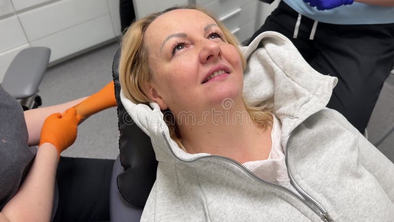 Fröhliche glückliche Frau, die in einem Stuhl bei der Zahnarzt Zahnbehandlung Arzt Freude Klinik privat auf Handschuhe gelegt stock video