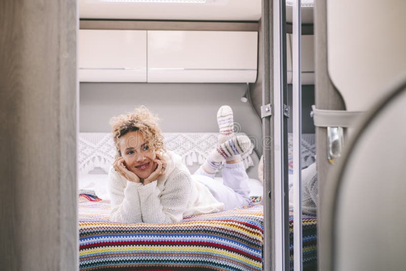 Fröhliche junge erwachsene Frau, die im Schlafzimmer in einem modernen Wohnmobil liegt. glückliche weibliche Leute unterhalten sic stockfotos