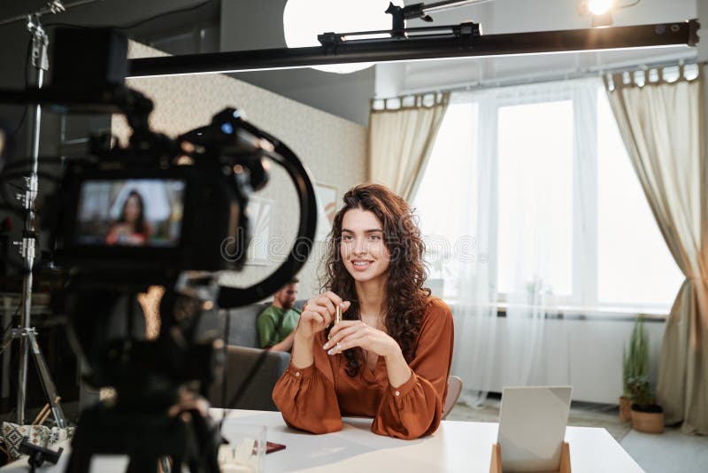 Fröhliche junge weibliche Redewendung während der kommerziellen Aufnahme im Studio stockbild