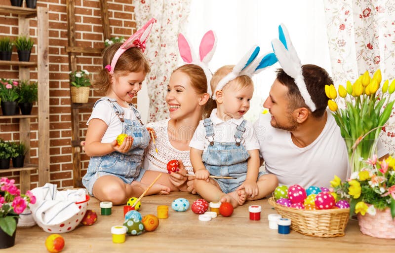 Fröhliche Ostern! Familienmutter, -vater und -kinder malen Eier für