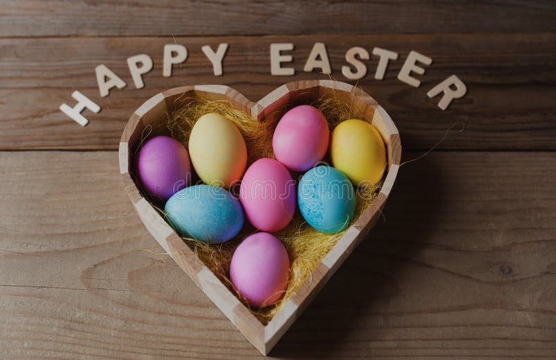 Fröhliche Ostern - farbige Eier in einem Herzen formten Schüssel stockfotografie Fröhliche Ostern - farbige Eier in einem Herzen formten Schüssel stockfotografie