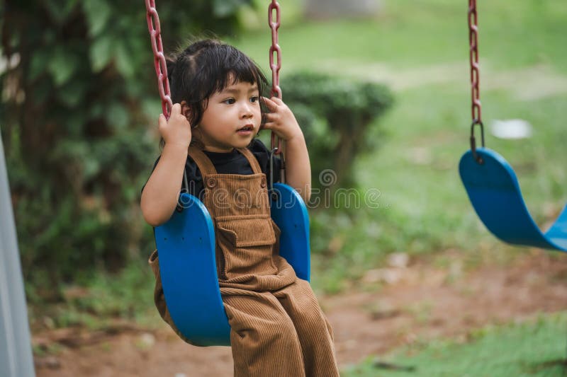 Fröhliches Kleinkind, das auf Schwung spielt stockbild