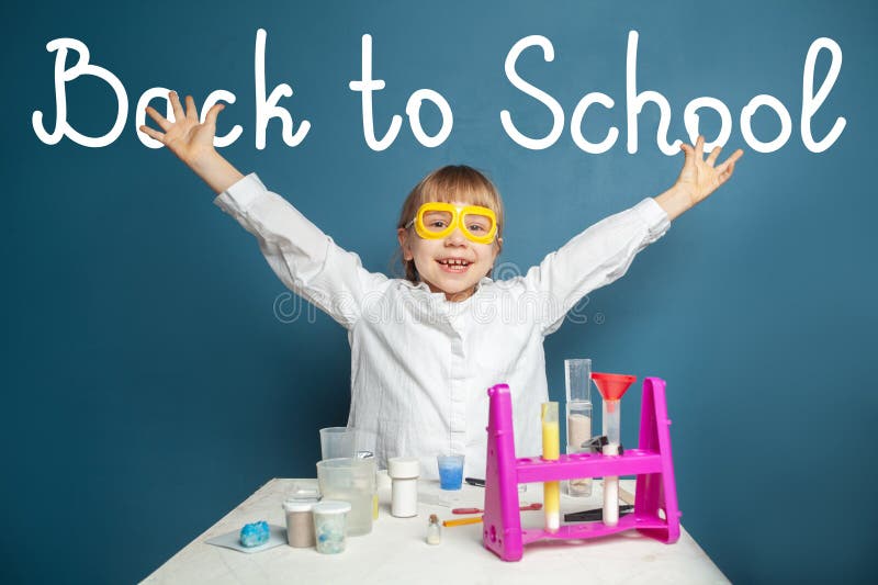 Fröhliches lächelndes Mädchen mit Händen hoch. ein Kind aus der Grundschule in Uniform auf blauem Hintergrund stockfotos