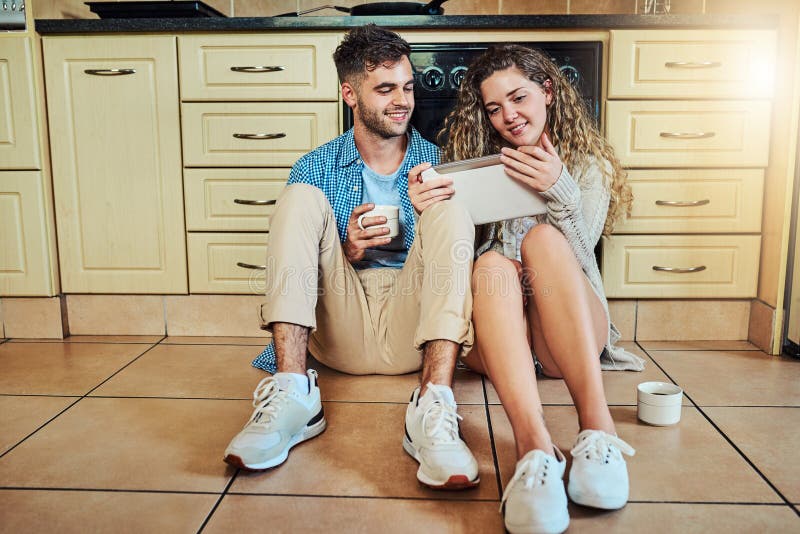 Fröhliches Paar Morgen und Kaffee mit Tablett in der Küche zum Durchstöbern von Nachrichten oder Streaming zu Hause. junger Mann lizenzfreies stockbild