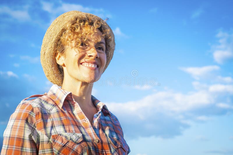 Fröhliches Porträt einer hübschen erwachsenen Frau, die im Hintergrund lächelt und die Freizeit vor einem blauen Himmel genießt. g stockfotos