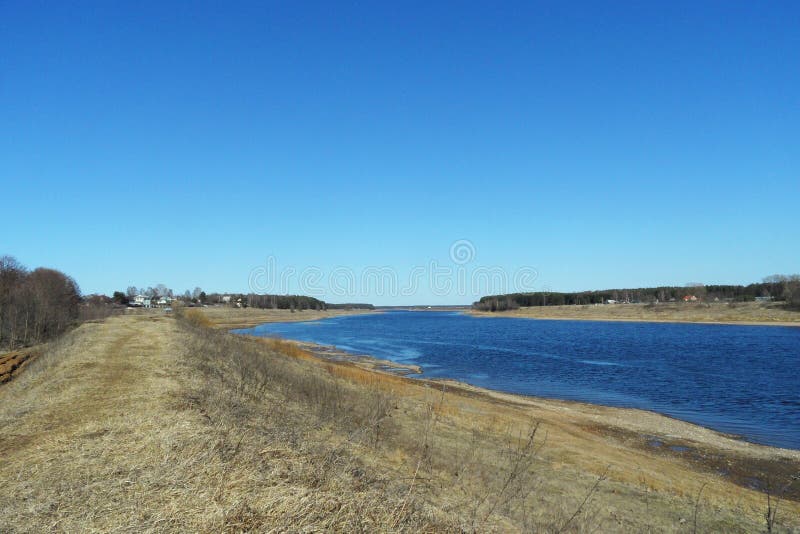Frühlingsflussbank mit getrocknetem trockenem Gras an einem sonnigen wolkenlosen Tag stockfotos Frühlingsflussbank mit getrocknetem trockenem Gras an einem sonnigen wolkenlosen Tag stockfotos