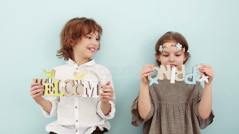 Frühlingsschießen im Studio Junge und Mädchen, die Zeichen mit Frühlingsdekor halten Kinder lachen, das Mädchen hält ein Zeichen