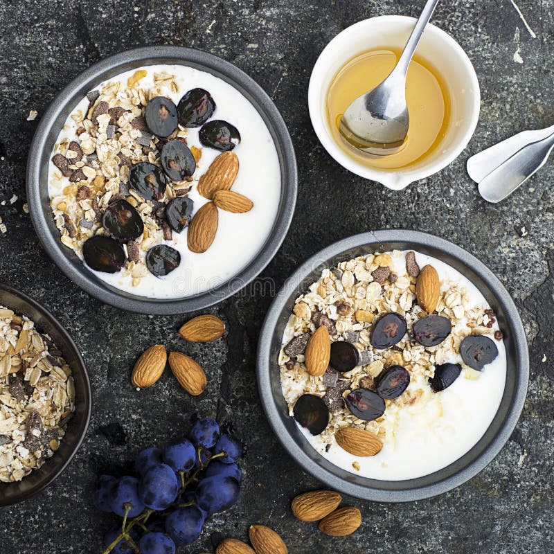 Frühstück von den gesunden Saisonbestandteilen: Granola, Flocken, Honig, dunkle Trauben, Mandeln in Umhüllung grauen pial auf a stockfotos Frühstück von den gesunden Saisonbestandteilen: Granola, Flocken, Honig, dunkle Trauben, Mandeln in Umhüllung grauen pial auf a stockfotos