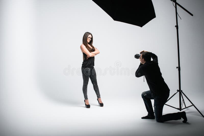 Fucilazione professionale della foto allo studio Il bello giovane modello sta sorridendo e posando il fotografo sta prendendo le immagine stock libera da diritti Fucilazione professionale della foto allo studio Il bello giovane modello sta sorridendo e posando il fotografo sta prendendo le immagine stock libera da diritti