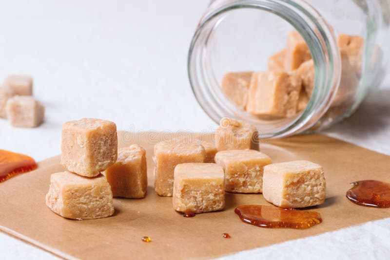 Fudge candy and caramel on baking paper and in glass jar, served over white tablecloth with jar of brown sugar. Fudge candy and caramel on baking paper and in glass jar, served over white tablecloth with jar of brown sugar