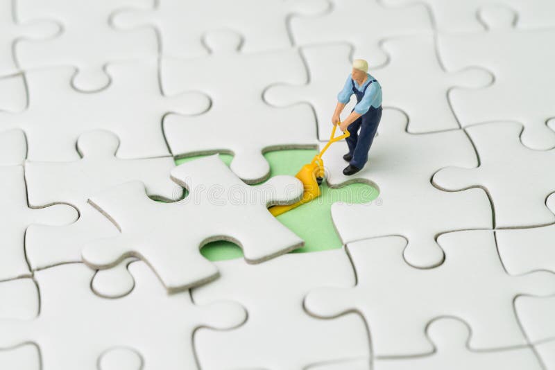 Fulfill the missing piece for business success strategy concept, miniature worker figurine using the forklift to complete the missing white jigsaw puzzle piece on pastel green background.