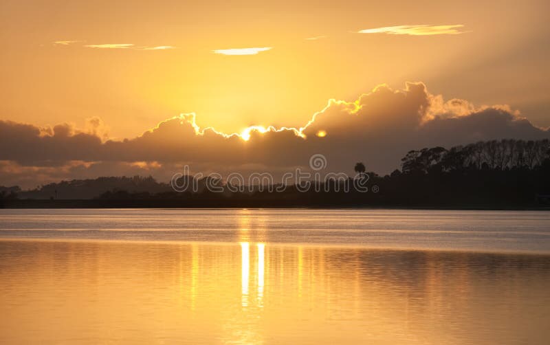 Brilho do sol nascente por entre as nuvens sobre a baía imagens de stock royalty free