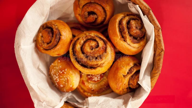 Full basket of sweet bread rolls with cinnamon and sesame seeds stop motion overhead shot