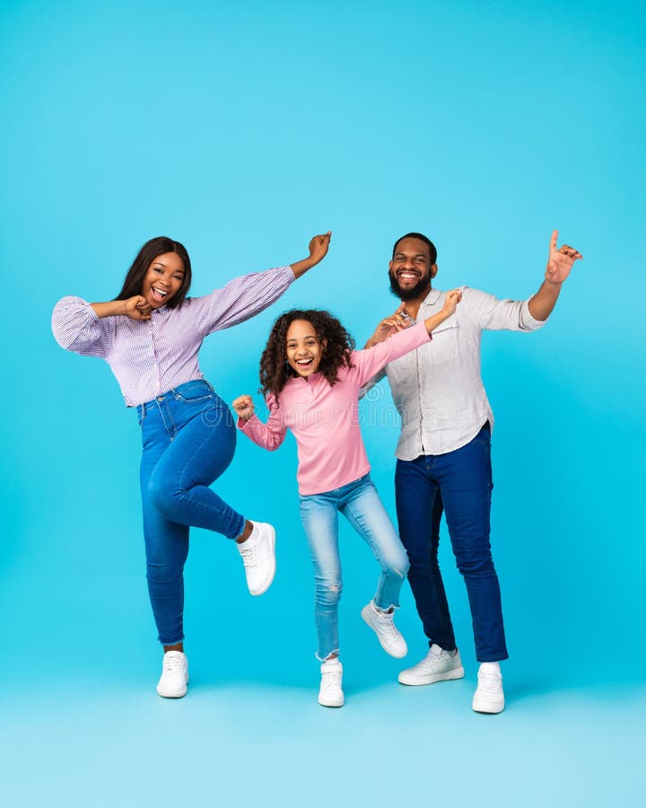 Portrait of emotional black family dancing at blue studio