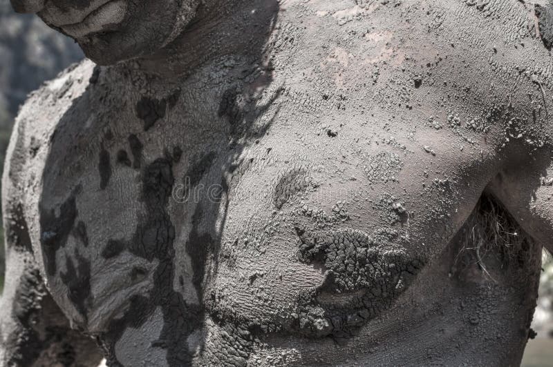 Closeup of upper torso chest area of muscular man covered in dry cracking mud outdoors in direct sunlight. Closeup of upper torso chest area of muscular man covered in dry cracking mud outdoors in direct sunlight