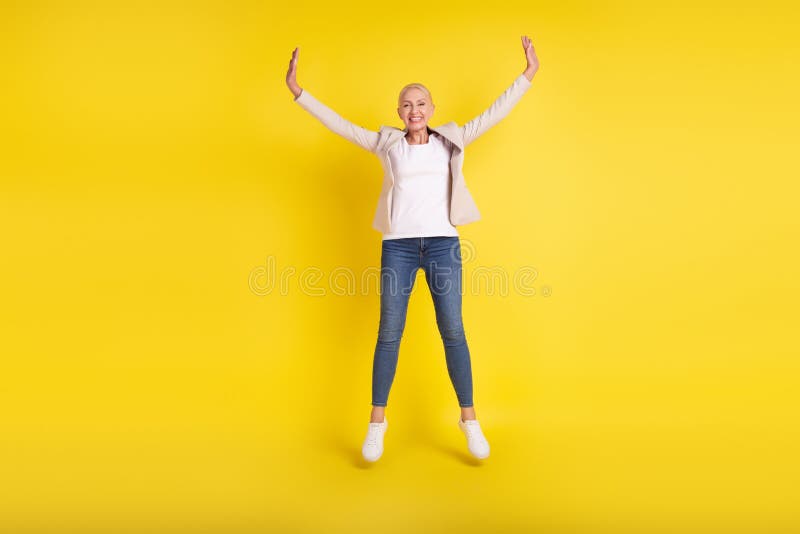 Full body photo of cheerful aged woman good mood jump up feel-young isolated over yellow color background royalty free stock photography
