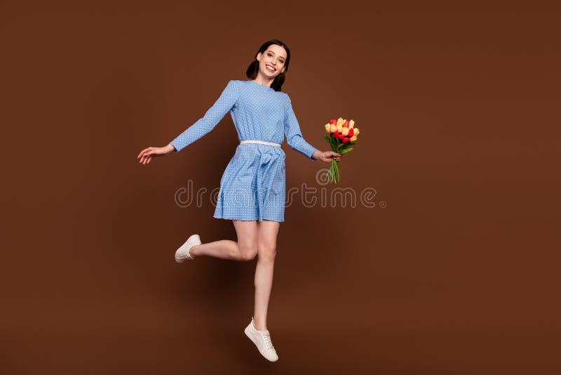 Full body photo of funky brunette lady jump with flowers wear blue dress isolated on brown background