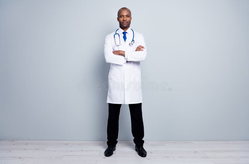 Full body photo of professional family doctor dark skin guy meet, patients virologist arms crossed wear white long lab coat neck tie pants shoes isolated grey color background. Full body photo of professional family doctor dark skin guy meet, patients virologist arms crossed wear white long lab coat neck tie pants shoes isolated grey color background