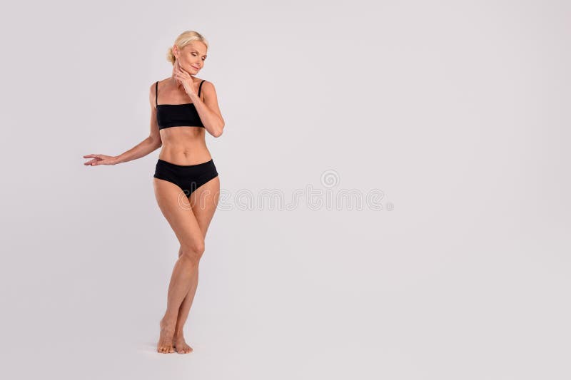 The Body Of A Young And Beautiful Woman In Female Underwear Showing Lingerie  To The Camera, Isolated On A Gray Background. Fashion Concept, Copy Space.  Stock Photo, Picture and Royalty Free Image.