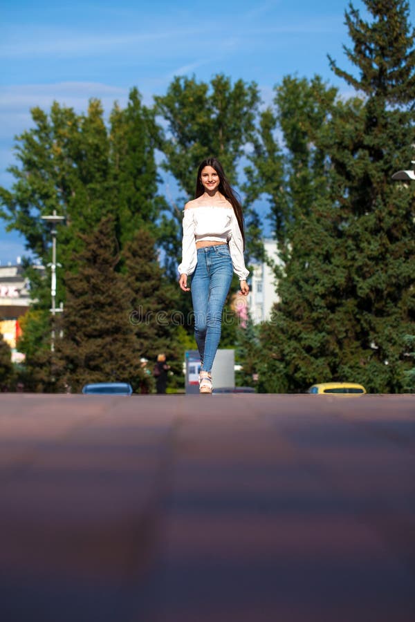 Young Beautiful Brunette Woman in Jeans and White Blouse Walking in ...