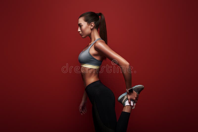 Full of energy. Sportswoman standing over red background, stretching her body royalty free stock photo Full of energy. Sportswoman standing over red background, stretching her body royalty free stock photo