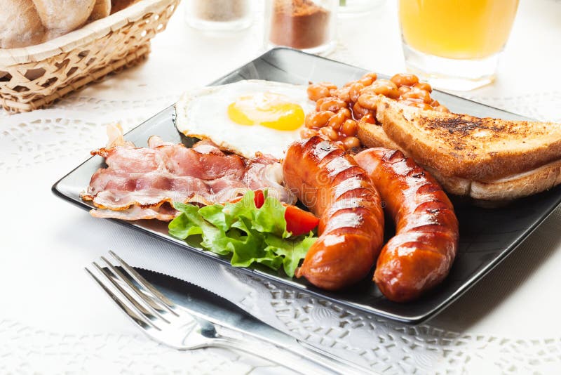 Full English breakfast with bacon, sausage, egg, baked beans and orange juice