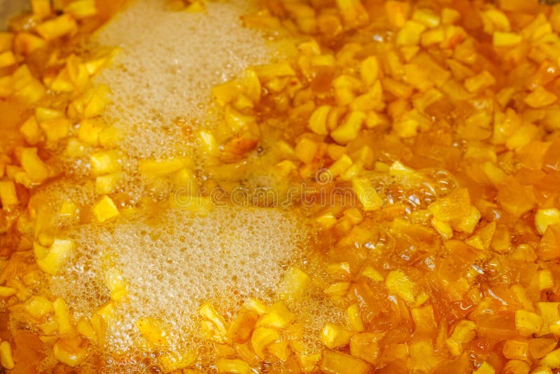 Full-frame background and texture of sliced yellow apples boiling in syrup during confiture cooking.