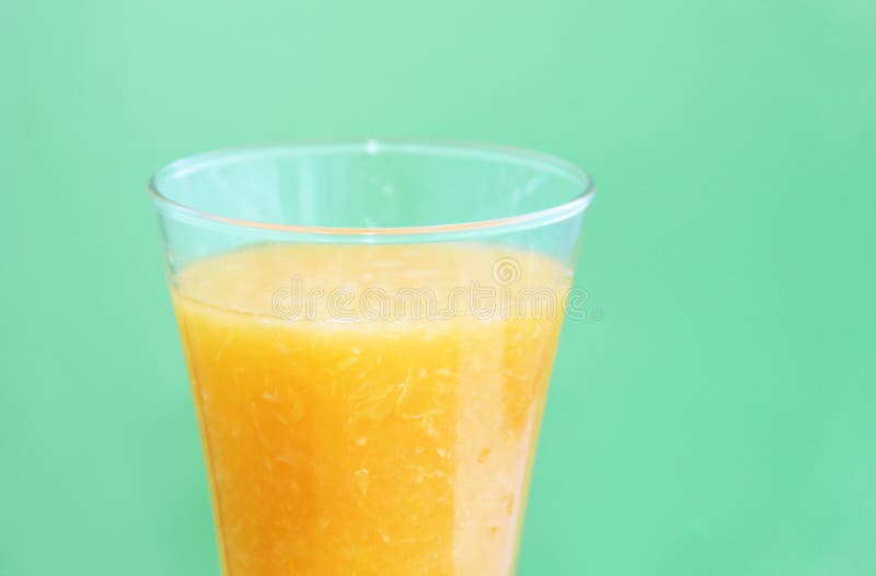 Full glass of orange juice on green background