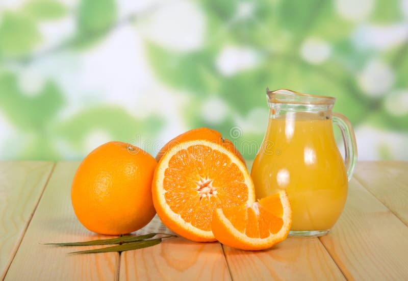 A Full Jug of Juice, Whole Oranges and Pieces of Fruit Stock Image
