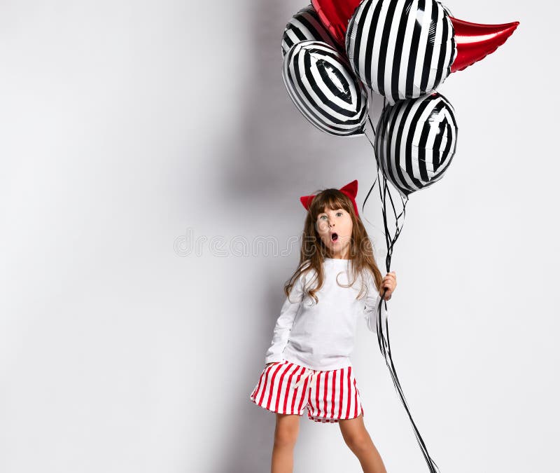 Full length of girl child with bunch of helium balloons