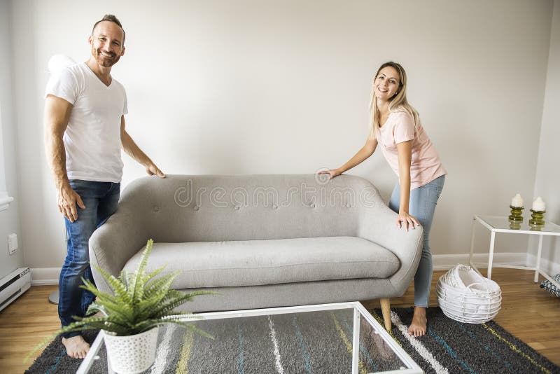 Full length of happy couple placing sofa in living room of new home royalty free stock photo Full length of happy couple placing sofa in living room of new home royalty free stock photo