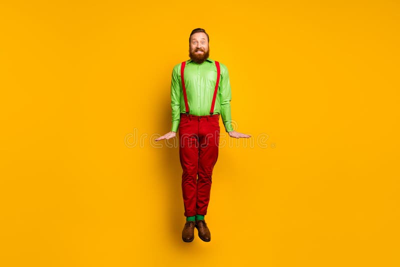 Full length photo of attractive funky guy jumping high up good mood rejoicing wear green shirt red suspenders pants