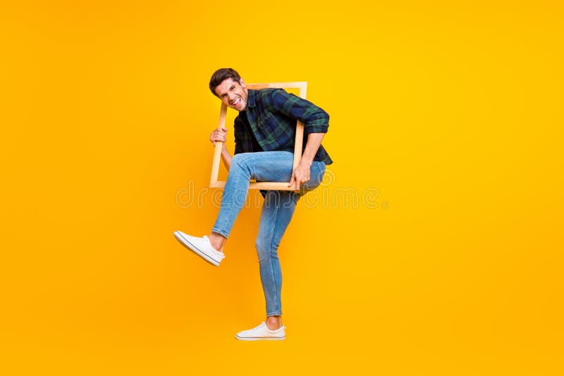 Full length photo of crazy guy holding wooden picture frame putting leg inside it wear casual checkered shirt and jeans