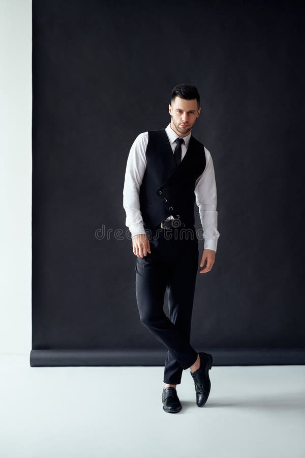 Full length portrait of handsome elegant man posing on black background