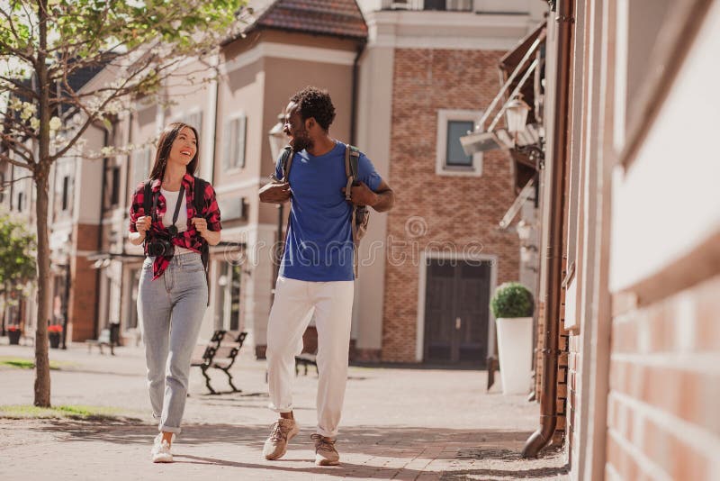 Full length shot of multiracial couple of tourists walking no the city and talking