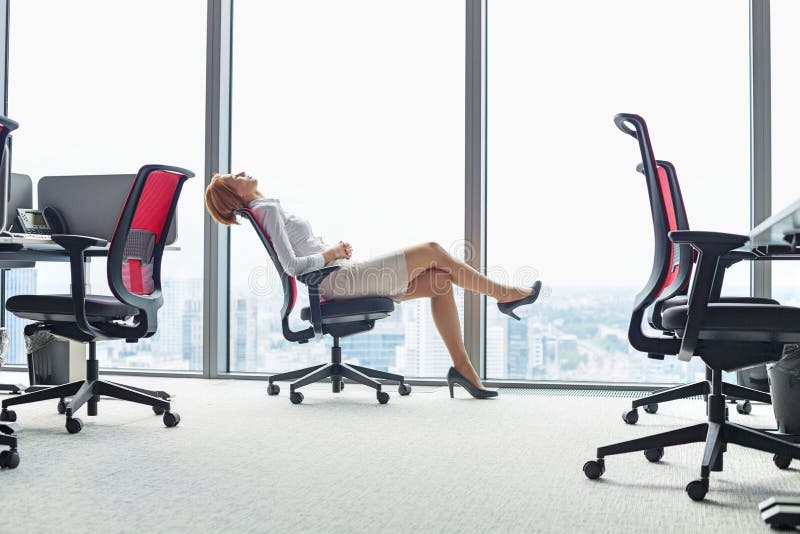 Full length side view of young businesswoman leaning back in chair at office