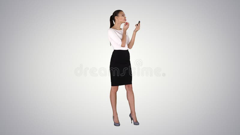 Beautiful woman, dyes her lips lipstick pink, looking in the mirror on gradient background. royalty free stock photos Beautiful woman, dyes her lips lipstick pink, looking in the mirror on gradient background. royalty free stock photos