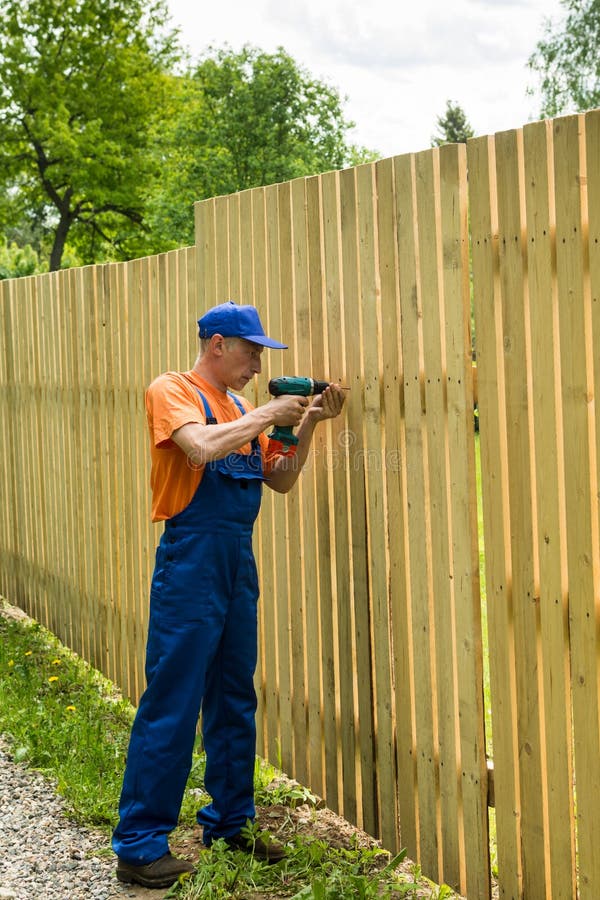 Fulllength Portrait Of Worker Constructing Wooden Fence Stock Image