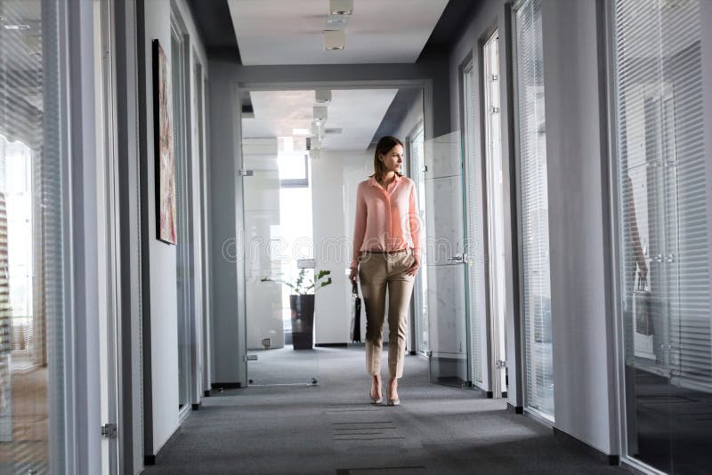 Full length of young businesswoman walking in office corridor