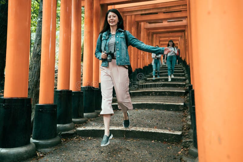 Girl cheerfully jumping down stair under red gate royalty free stock photo