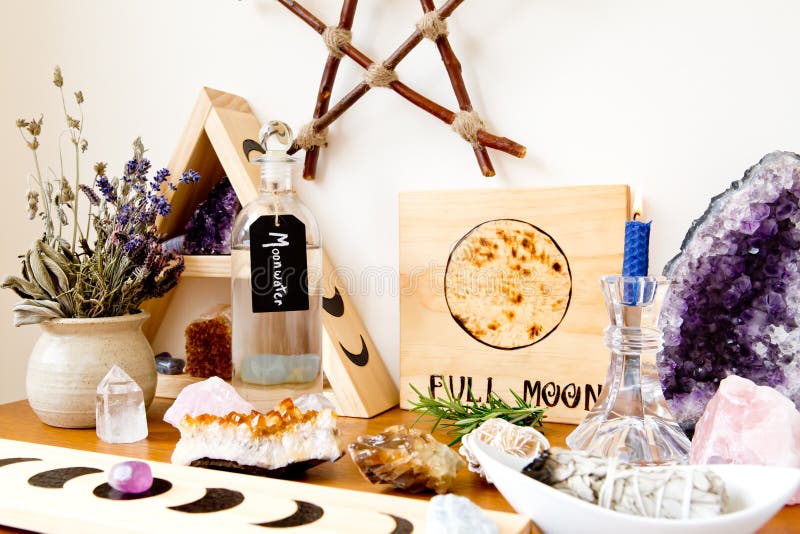 Full Moon Altar setup for ritual, with herbs, crystals, candle, bottle of moonwater and branch pentagram