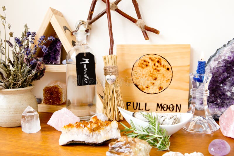 Full Moon Altar setup for ritual, with herbs, crystals, candle, bottle of moonwater and branch pentagram