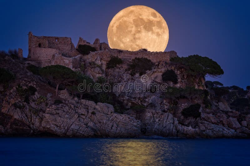 Full moon over the old castle in Costa Brava in a holiday village Fosca , Spain