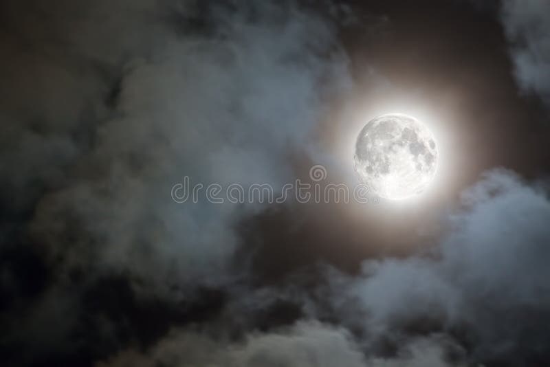 Spooky white clouds and a full moon with a halo against a black night sky. Spooky white clouds and a full moon with a halo against a black night sky